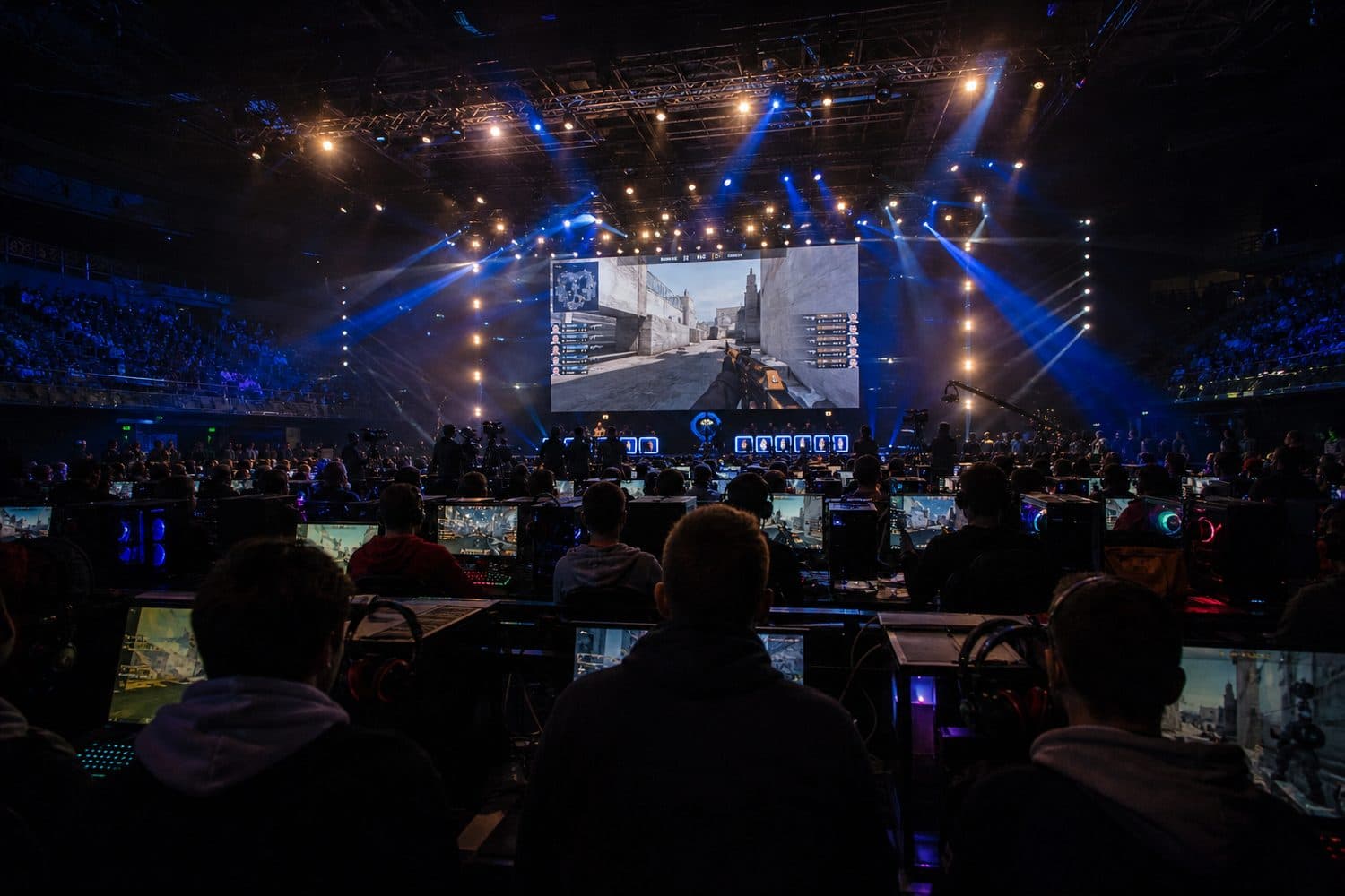 A packed LAN arena with rows of PCs facing a tournament stage